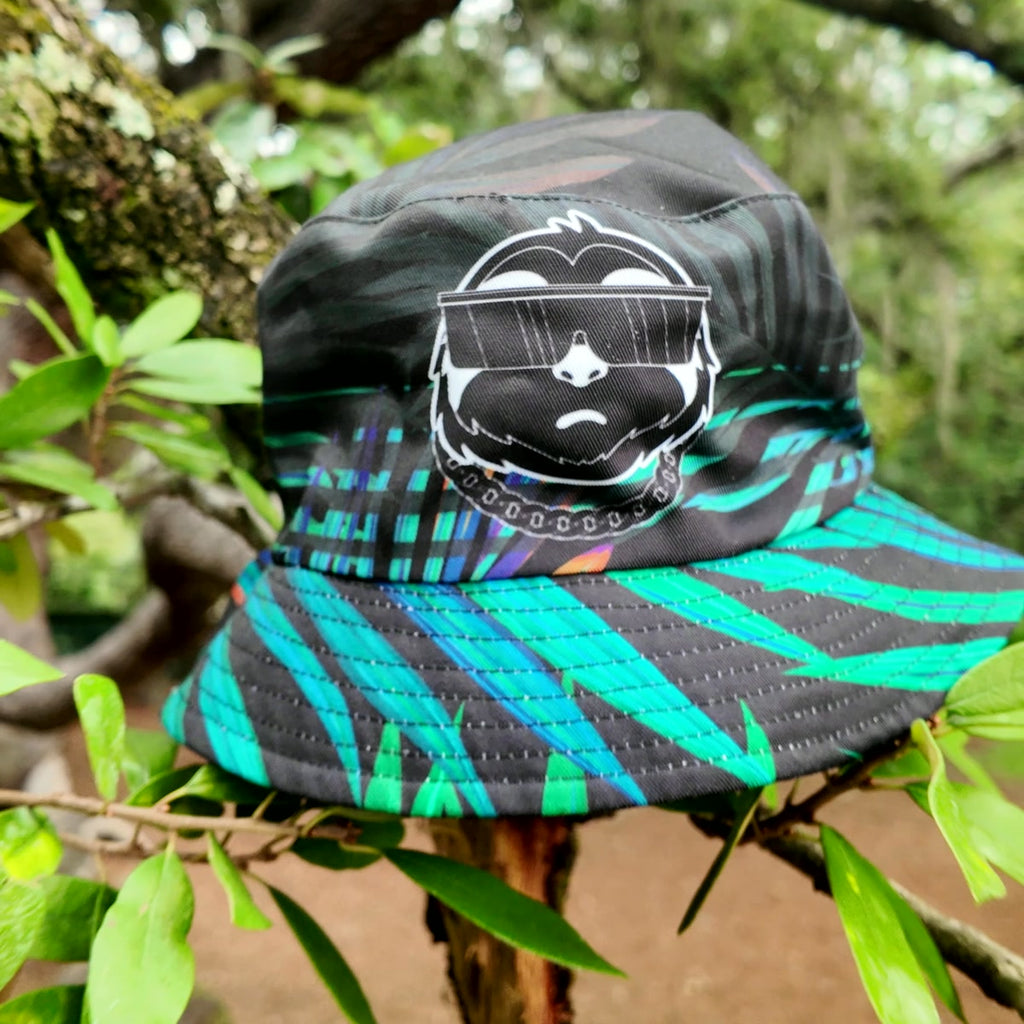 SLOTH reversible bucket hat, jungle side: black with a turquoise palm-leaf print and the SLOTH character patch