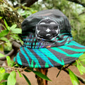 SLOTH reversible bucket hat, jungle side: black with a turquoise palm-leaf print and the SLOTH character patch
